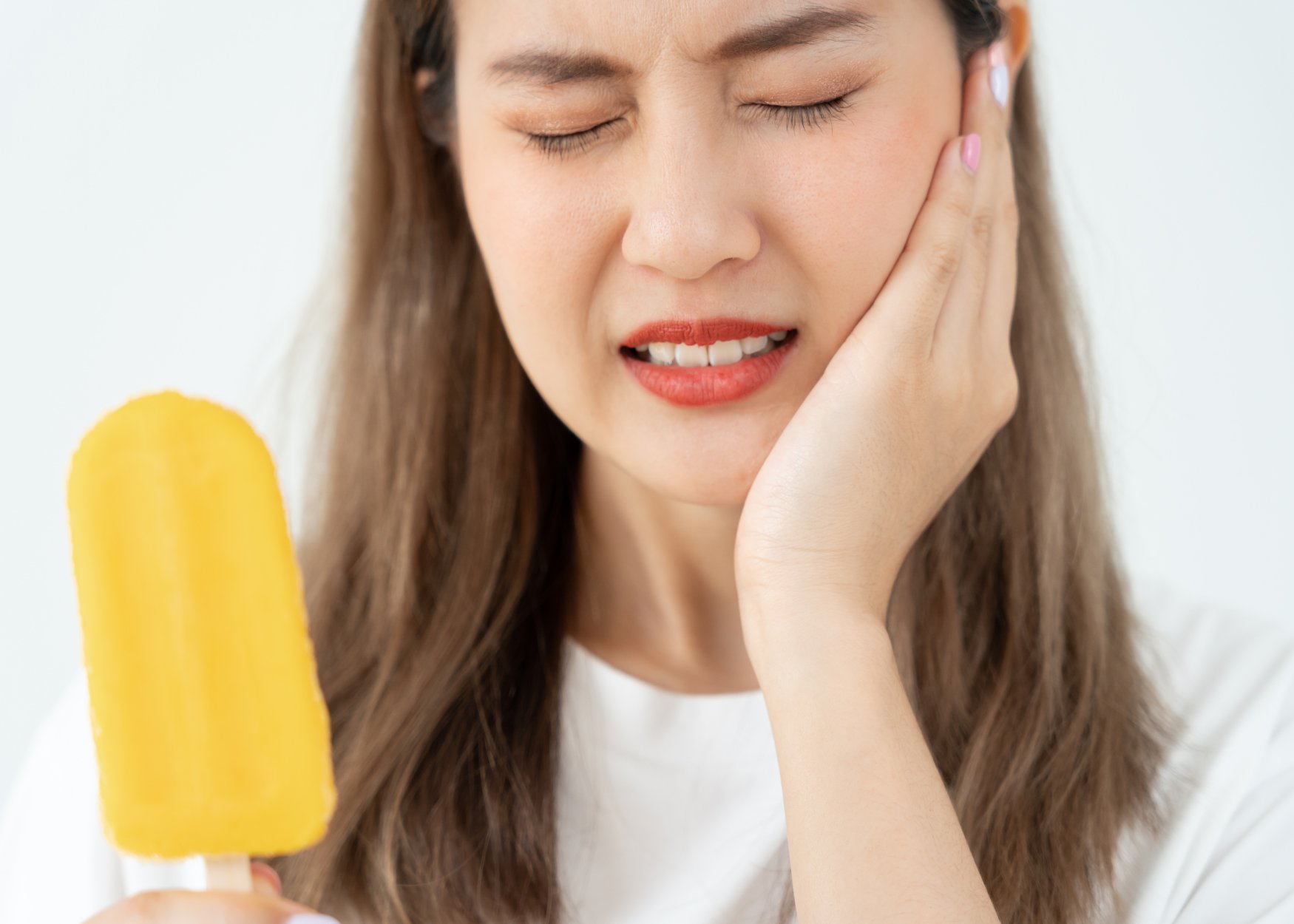 close up of an person holding their jaw, reflecting tooth sensitivity while having icecream.